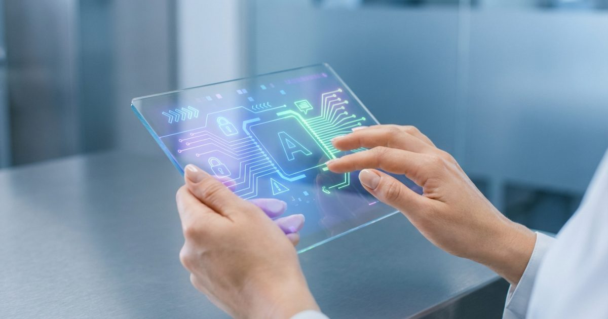 Mains manipulant une tablette transparente lumineuse. L'écran affiche des circuits, icônes de cadenas et la lettre A, évoquant l'IA et la sécurité.