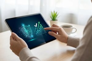 Mains tenant une tablette affichant un bouclier de sécurité et un graphique ascendant, symbolisant fiabilité et performance.